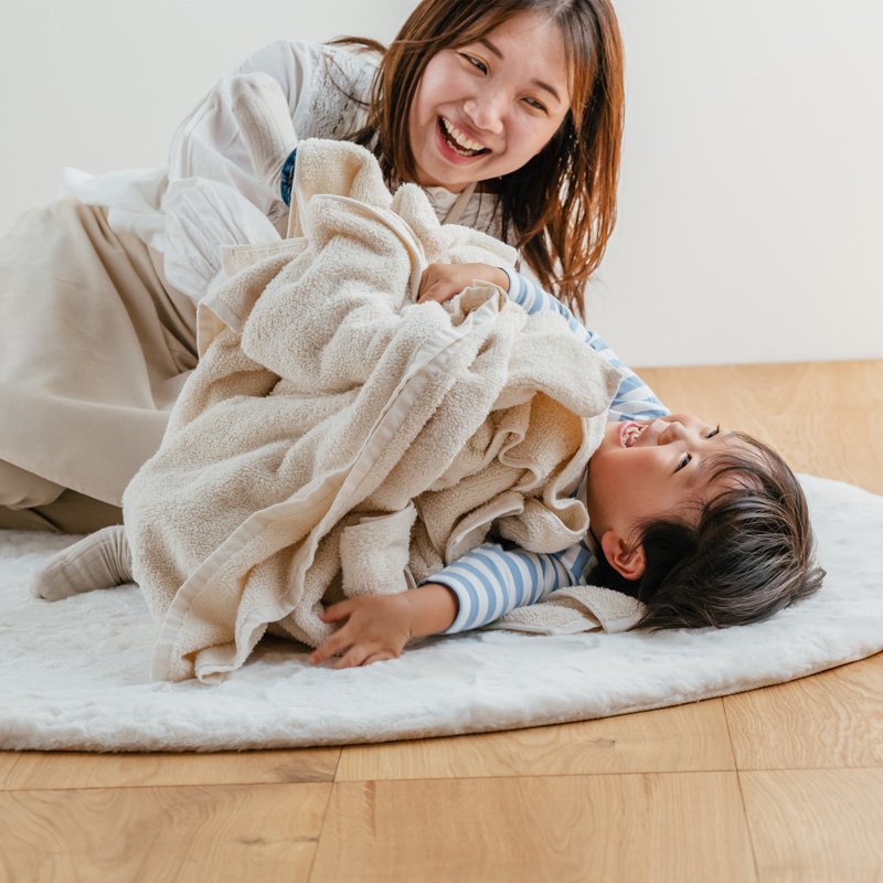 タオルに包まる楽しそうな赤ちゃんとお母さん