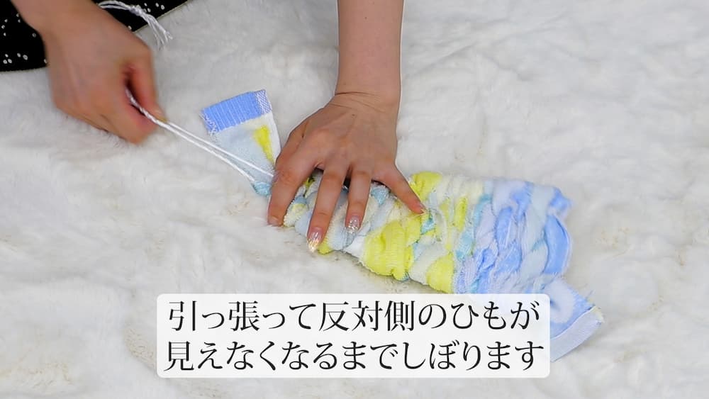 引っ張って反対側のひもが見えなくなるまでしぼります